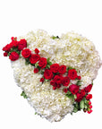 A heart-shaped arrangement of white hydrangea, white roses, and red roses on an easel.